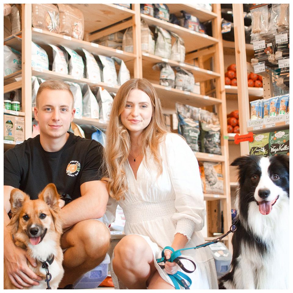Zespół BarkShop z psami między drewnianymi półkami sklepu stacjonarnego